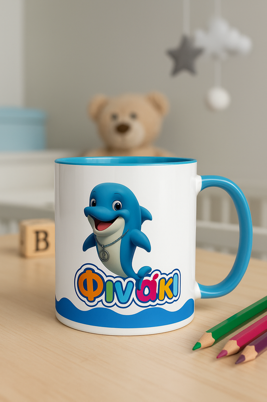Children's mug with a cartoon dolphin and colorful text on a wooden table, with a teddy bear and toys in the background.