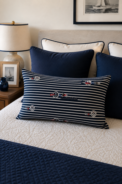 Decorative pillows on a bed with a striped pattern and nautical design.