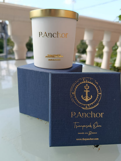 Luxury aromatherapy candle by P.Anchor in white jar with gold lid, displayed on navy blue gift box with gold anchor logo – Made in Greece
