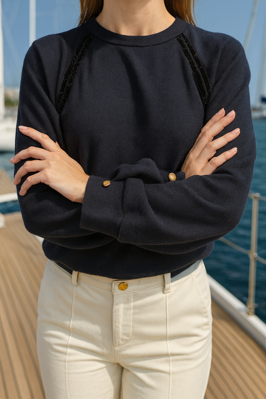 Person wearing a black sweater and beige pants on a boat deck.