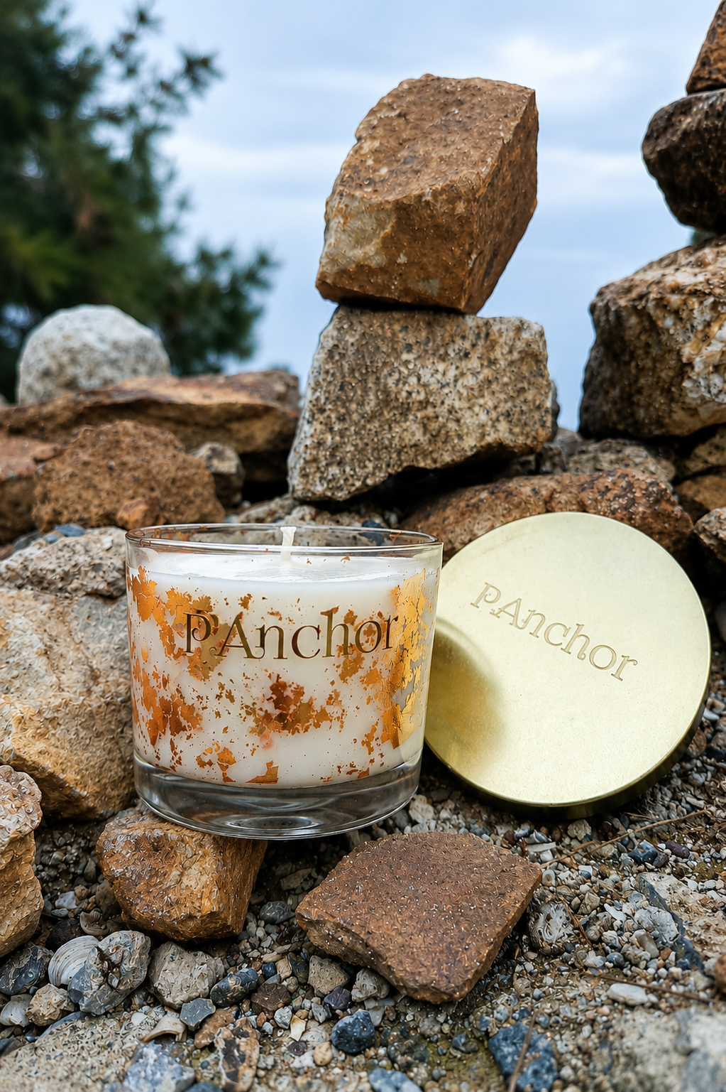 Candle and lid with 'P.Anchior' branding on a rocky surface